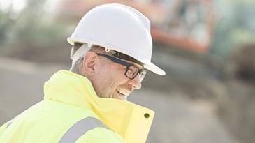 Happy older male construction worker wearing a hard hat.