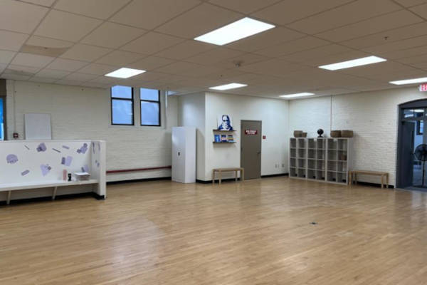 Spacious room with wood floors, white walls, featuring cubbies and a wall mural near the door.