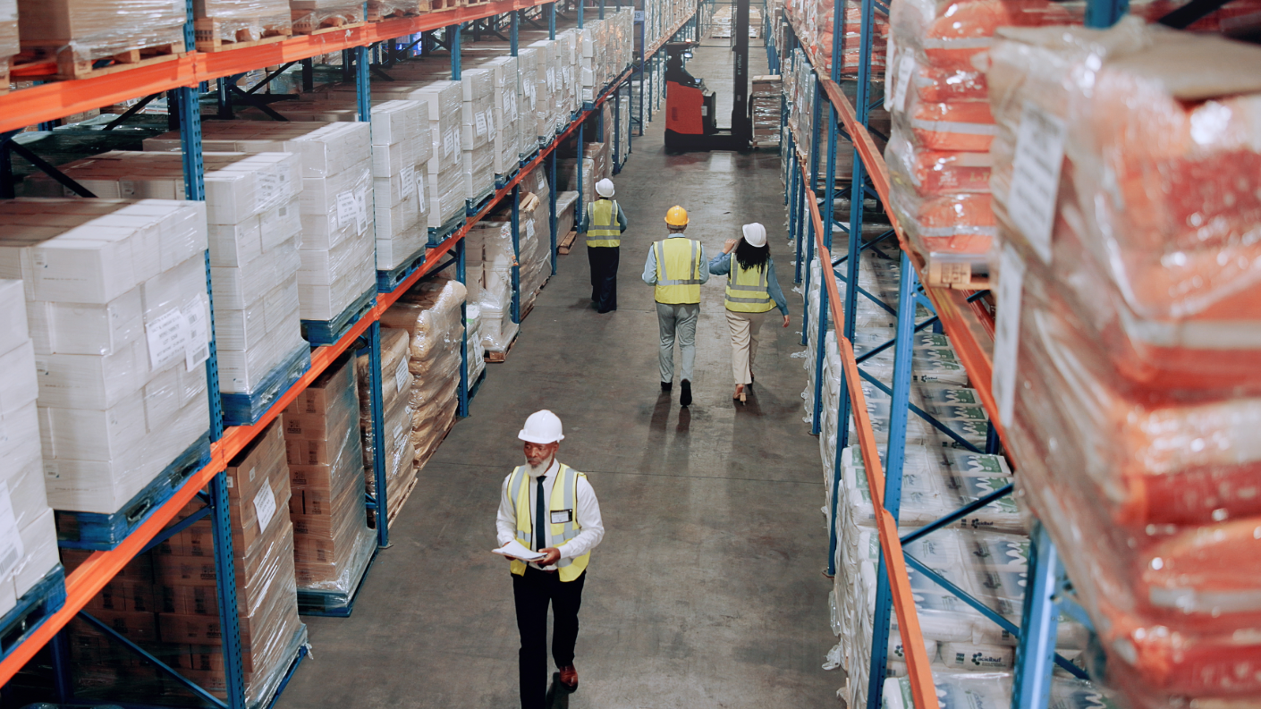 Workers wearing hardhats walking through a warehouse