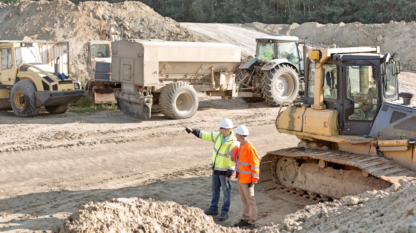 Two construction workers overlooking a large construction site