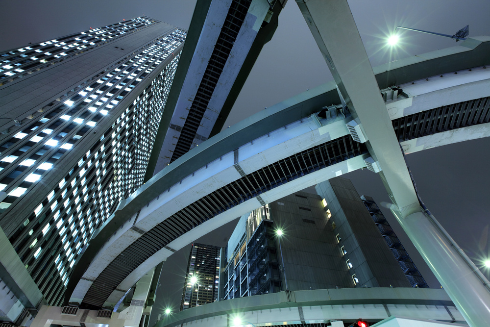 an image of a rail system and commercial building in grey and black against a gray sky