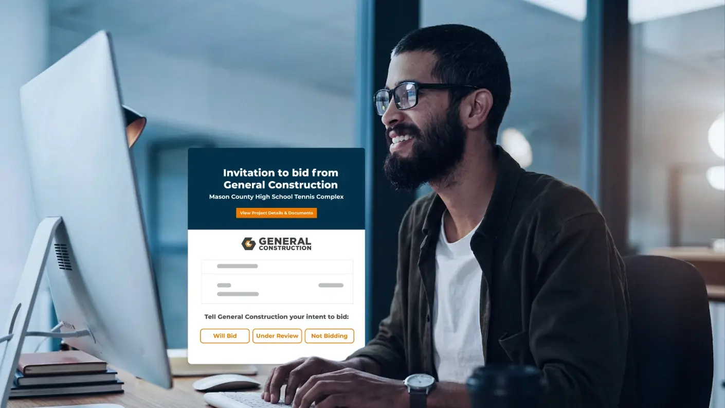 man typing on a computer next to a constructconnect bid invitation