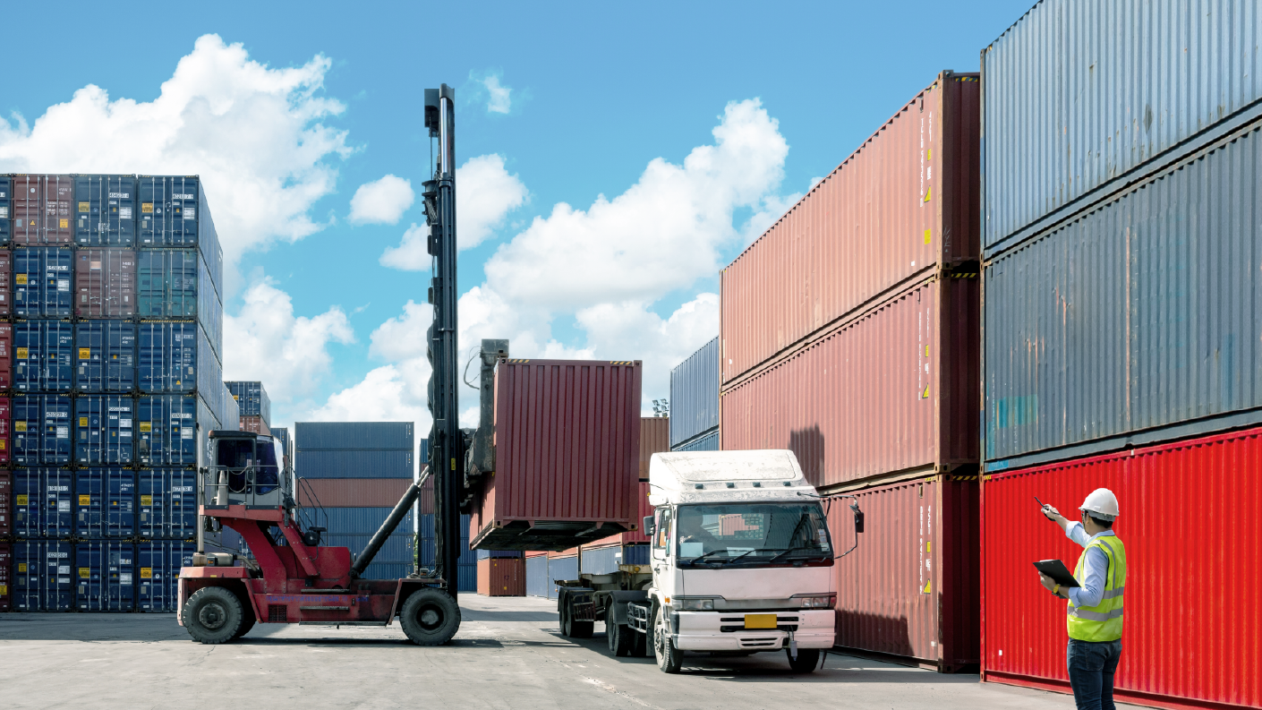 A forklift is moving shipping containers with construction materials